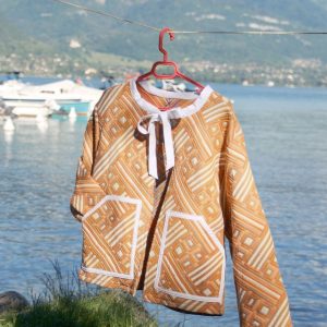 Veste dans les tons orange et creme avec un noeud blanc au col suspendu au bord du lac d'Annecy